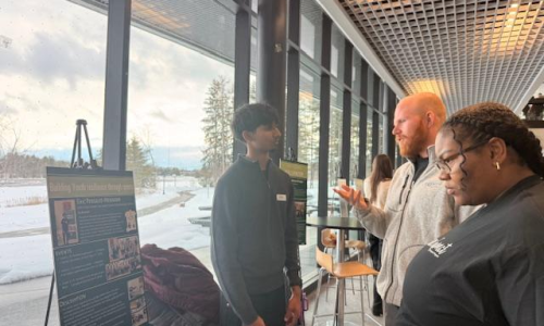 Student explains his project to two adults at a conference.