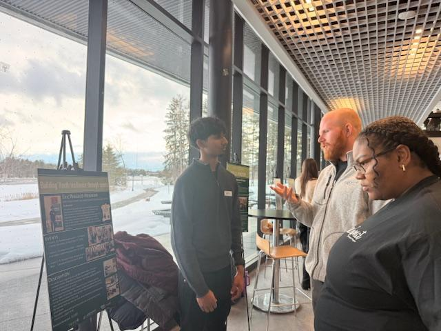 Student explains his project to two adults at a conference.