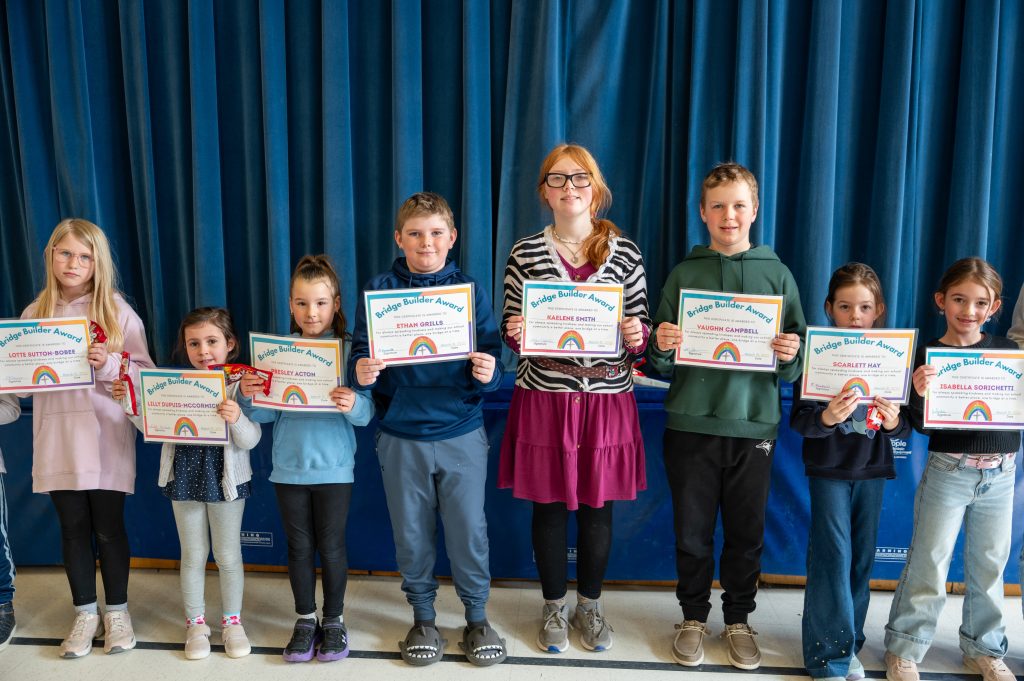 Eight students stand together holding award certificates.