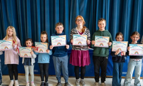 Eight students stand together holding award certificates.