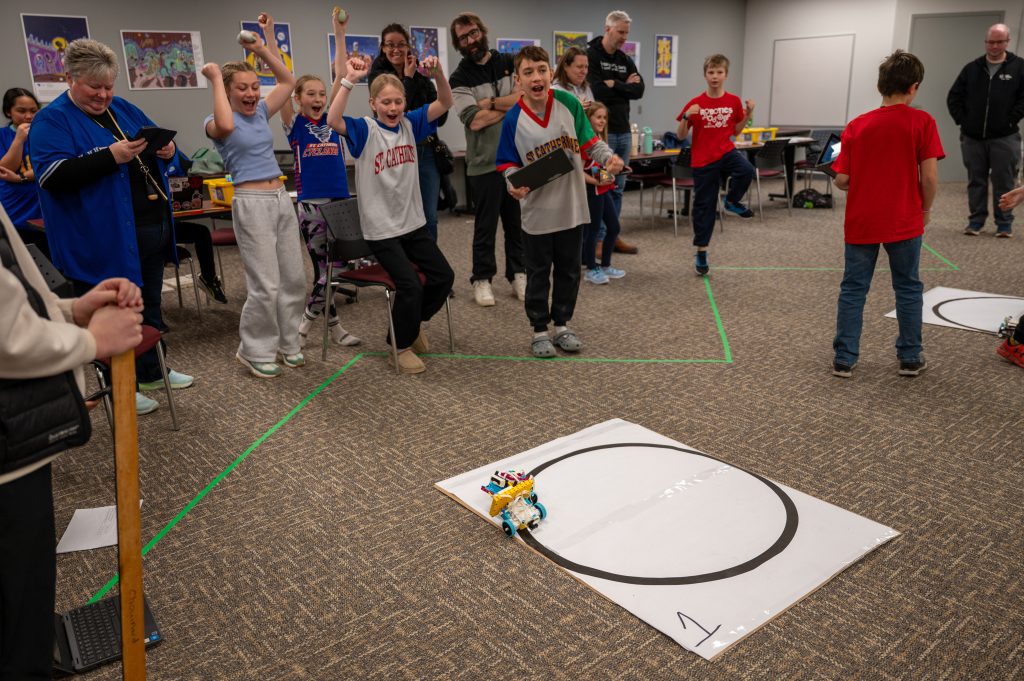 A group of students celebrate after winning a leg of a robotics competition.