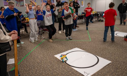 A group of students celebrate after winning a leg of a robotics competition.