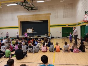 Students participate in an active Indigenous Land Acknowledgment in a school gymnasium.