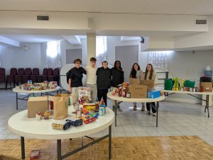 Six students stand with food collected during a community drive.