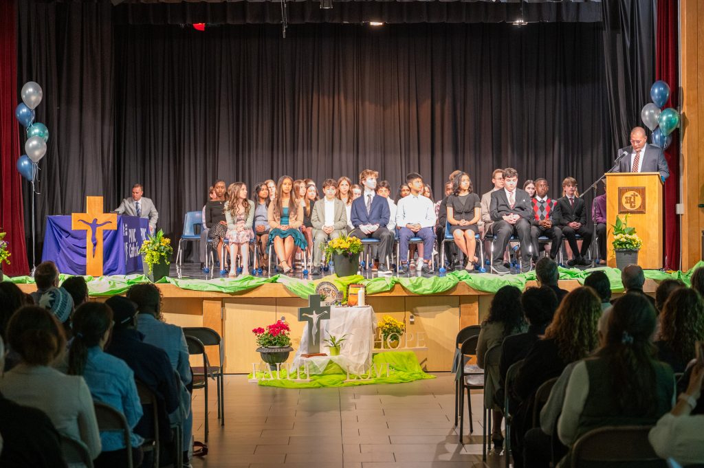 Students gather on a stage while wearing formal wear for an awards ceremony.