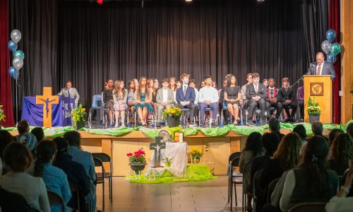 Students gather on a stage while wearing formal wear for an awards ceremony.