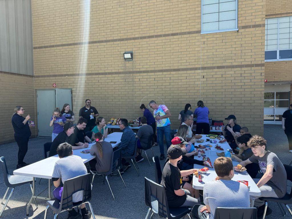 Students, teachers and their families gather for a community barbecue lunch.