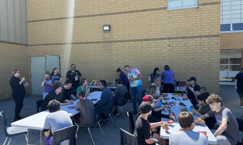 Students, teachers and their families gather for a community barbecue lunch.