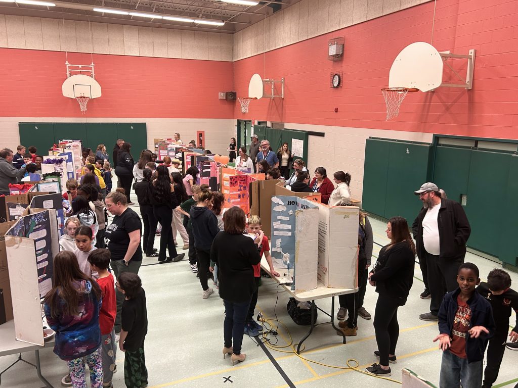 A science fair is held in a school gymnasium.