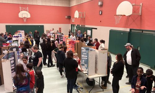 A science fair is held in a school gymnasium.