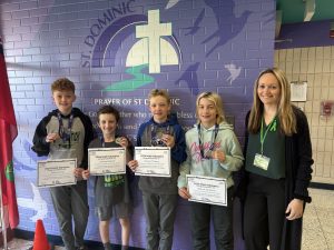 Four students and a teacher pose for a photo after winning medals at the Math Olympics competition.