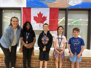 Four students and a teacher pose for a photo after winning medals at the Math Olympics competition.