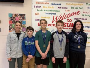 Four students and a teacher pose for a photo after winning medals at the Math Olympics competition.