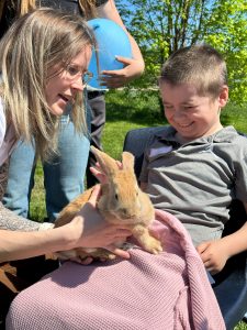 A student holds a rabbit while accompanied by an adult.