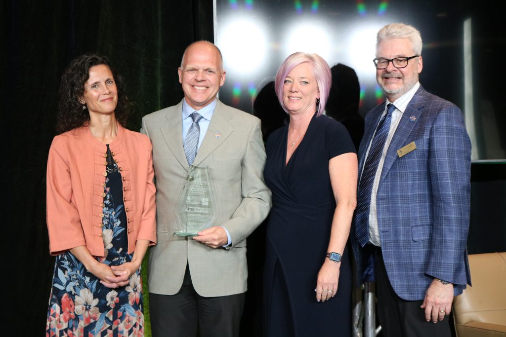 Four adults pose for a photo at an awards ceremony. The second person from the left, Alex Duketow, was named the Dick Hopkins Award recipient by Skills Ontario.