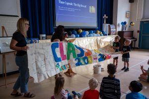 Students hold up a banner that was found inside of a time capsule.e